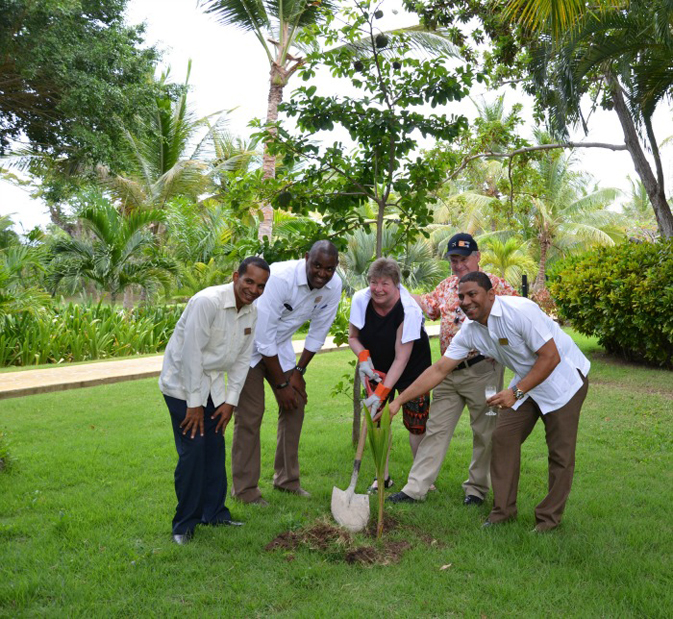 Lush gardens is a hallmark of this resort, and guests are often asked to participate when the resort plants a tree, which happens every 15 days - (MC staff with two hotel guests):