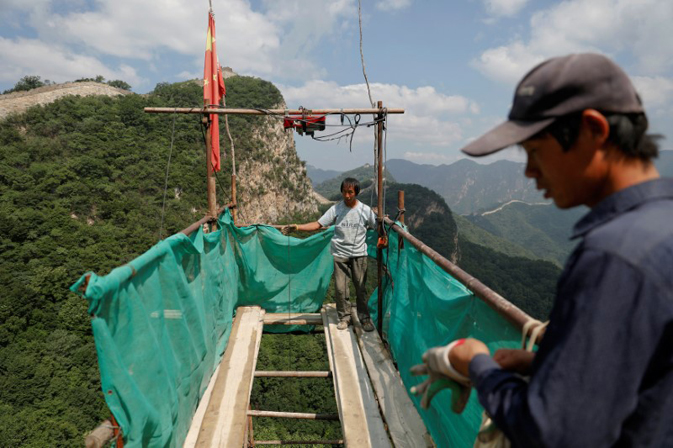 People wait for bricks and other equipment to be delivered as they work on the reconstruction of the Jiankou section of the Great Wall, located in Huairou District, north of Beijing, China, June 7, 2017. REUTERS/Damir Sagolj