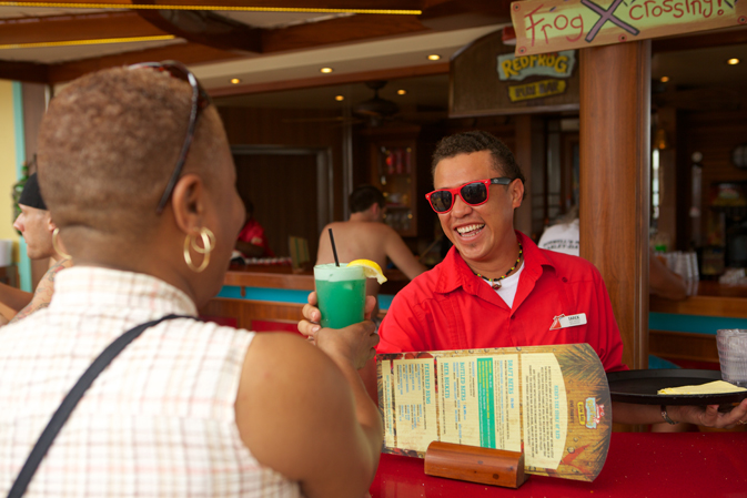 Smiling waiter delivers fruity drink to cruiser